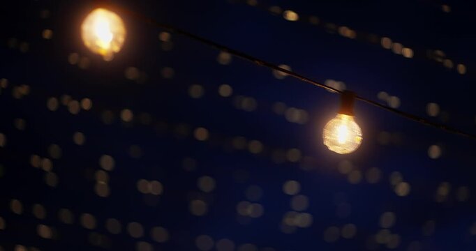 Warm hanging string lights glowing over an outdoor evening scene