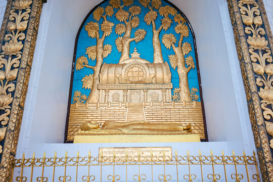 A golden relief panel depicting the reclining Buddha under Bodhi trees with a stupa is framed by an elaborate decorative border at the World Peace Pagoda.