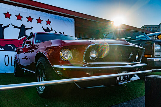 Red Ford Mustang with white racing stripes, parked in a grassy area at an event or show Iconic galloping horse emblem on the front grille Background includes a lar - Kyiv, Ukraine - September 21, 2025