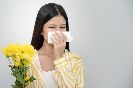 Pollen Allergies, asian young woman sneezing in a handkerchief or blowing in a wipe, allergic to wild spring flowers or blossoms during spring. allergic reaction, respiratory system problems