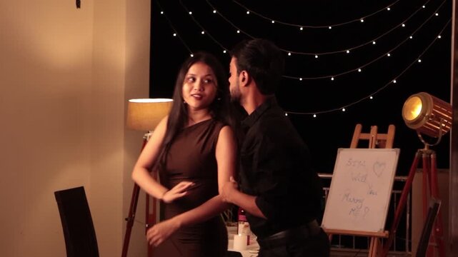 Romantic couple performing partner dance during intimate candlelight dinner date celebration