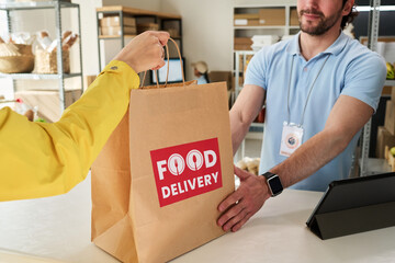 Young man handing food delivery order to customer at pickup counter, showing takeaway service and retail fulfillment. Ideal for delivery apps, local business marketing, e commerce © pressmaster
