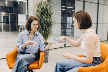 Fototapeta premium Young woman offering water to distressed friend during support
