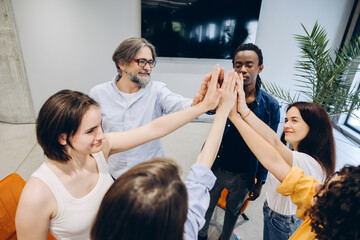Obraz premium Diverse business team showing unity with high five in modern office