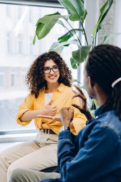 Diverse woman and African American man communicating using sign language sitting in modern office