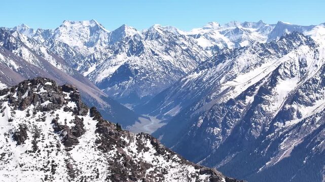 Ak Su mountains with snowy peaks, aerial high rise. Kyrgyzstan landscape, sunny day. Travel