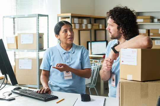 Young warehouse workers discussing parcel pickup process at order collection desk, coordinating delivery logistics. Ideal for e commerce fulfillment, retail operations marketing