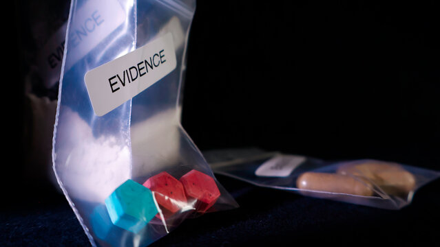 Plastic evidence bags containing white powder, colored pills, and capsules symbolizing drug trafficking, crime investigation, and illegal substance control for legal proceedings