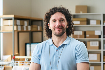 Fototapeta premium Portrait of young man managing order pickup point in delivery workspace, representing retail logistics and fulfillment. For ecommerce, courier service, small business marketing