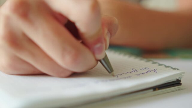 Close up shot of a hand writing text with a pen in a notebook. Macro shot of a student doing homework. University student studying and writing notes for an exam. Education concept.