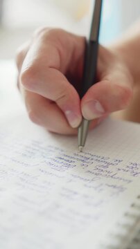 Close up shot of a hand writing text with a pen in a notebook. Macro shot of a student doing homework. University student studying and writing notes for an exam. Education concept.