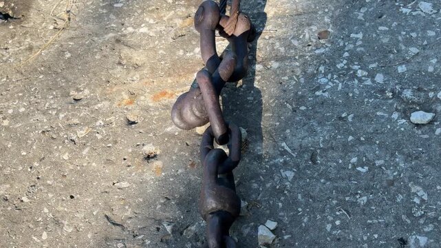 Rusty Anchor Chain: A weathered, heavy-duty anchor chain lies on a rough concrete surface, showing signs of rust and wear from its time at sea.