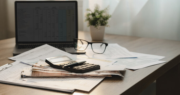 Tax forms, receipts, calculator, and financial documents arranged on a desk with laptop and ample copy space, supporting tax filing, accounting review, expense calculation, and business documentation.