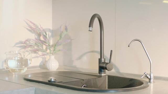 Clear fresh water dripping from broken kitchen faucet into sink at home.
