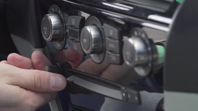 Man hand adjusting car temperature sensor dial on vehicle dashboard close up.