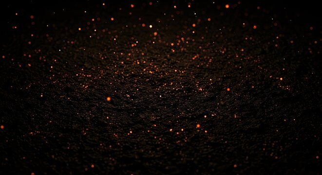Orange sparks and glowing embers on dark textured ground