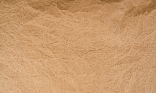 Old wrinkled brown paper texture background. Rough brown kraft paper texture. Recycle cardboard sheet. Rustic background pattern design. Closeup crumpled paper bag. Grunge and creased parchment.