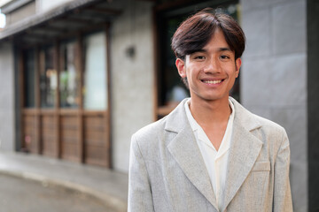 Obraz premium Portrait of smiling non-binary Thai Isan professional on street