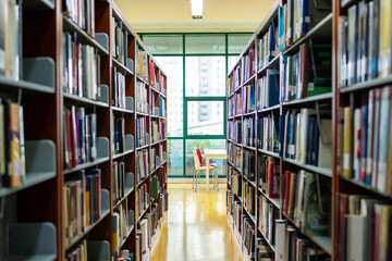 Shot of library, long aisle of a quiet library filled with tall bookshelves on both sides.  © Kawee