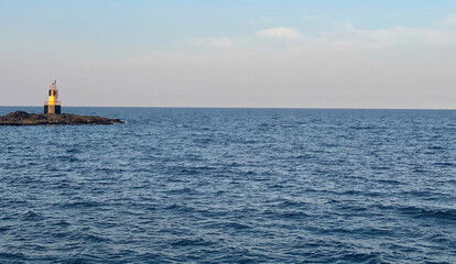 Obraz premium Tranquil ocean view with a distant beacon on a rocky island
