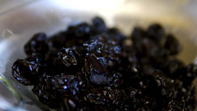 Washing dried prunes in glass bowl before cooking homemade recipe preparation process close up