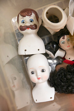Collection of vintage porcelain doll heads and parts in a container