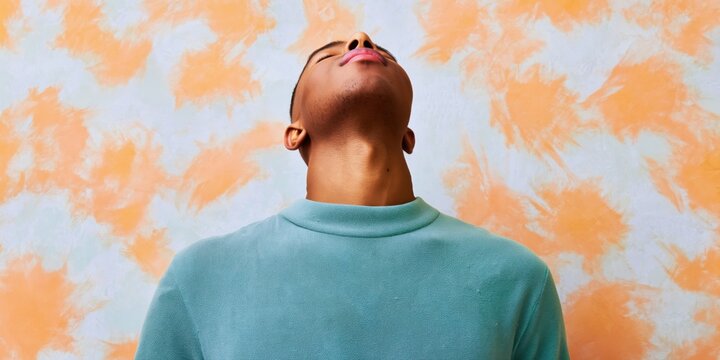 Person in teal shirt tilting head back for deep breathing against a creative patterned wall for mental health blog, wellness website and stress relief advertising