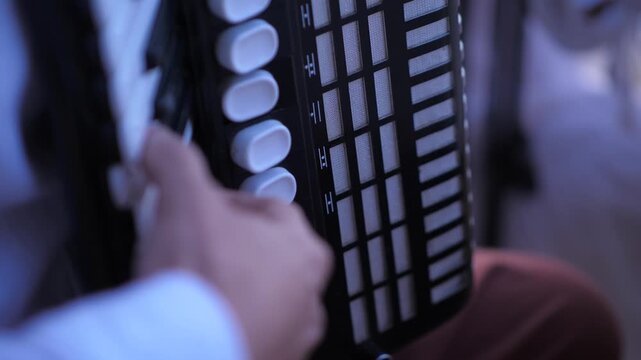 Man musician masterfully playing accordion on blurred background close-up hand.