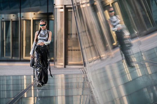 Stylish woman in futuristic outfit walks downtown