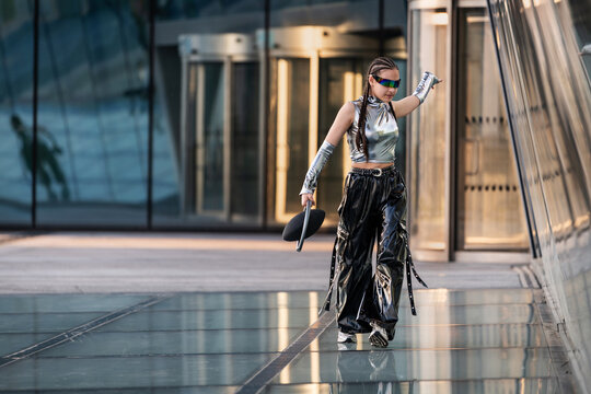 Young woman in futuristic silver outfit walks downtown