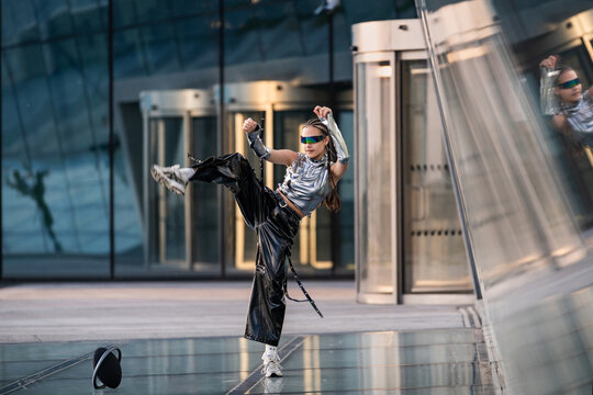 Young woman in futuristic outfit does a high kick