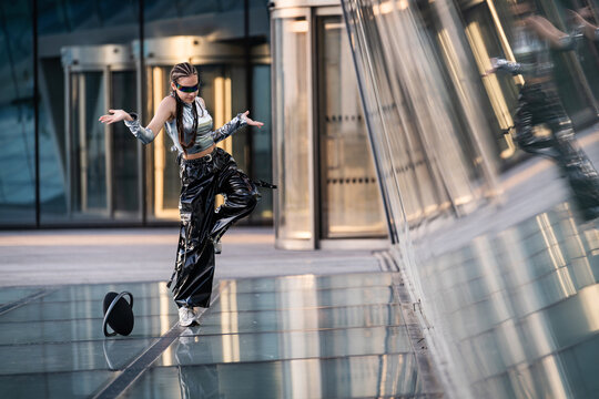 Stylish woman in futuristic outfit dancing outdoors