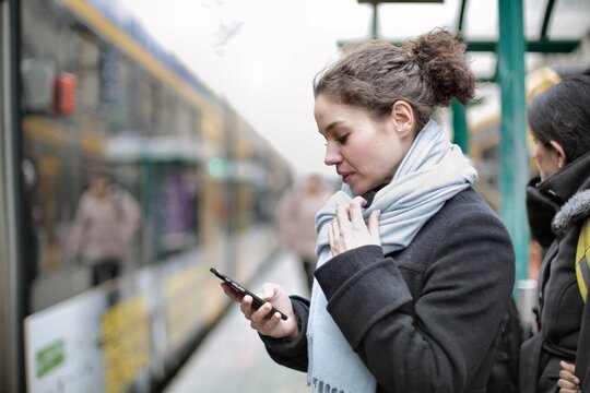 Woman checks her phone while waiting for train