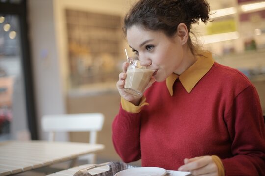 Young woman in red sweater enjoying coffee at a cafe