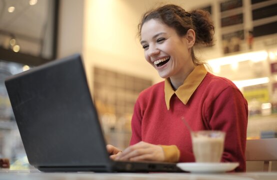 Joyful young woman laughing at her laptop