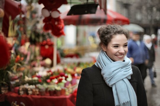 Smiling woman walking past outdoor flower stall