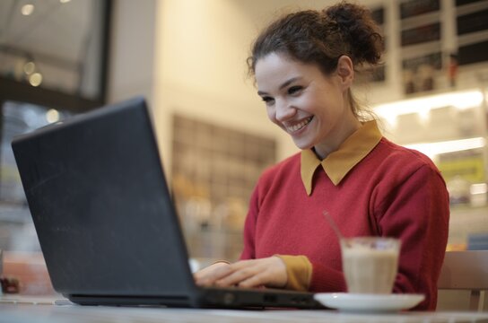 Happy young woman working on laptop at cafe