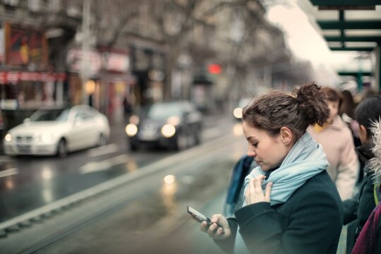 Young woman using smartphone at city bus stop