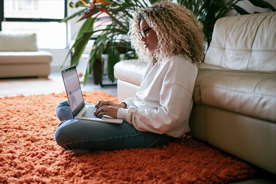 Young woman with curly hair works on laptop at home