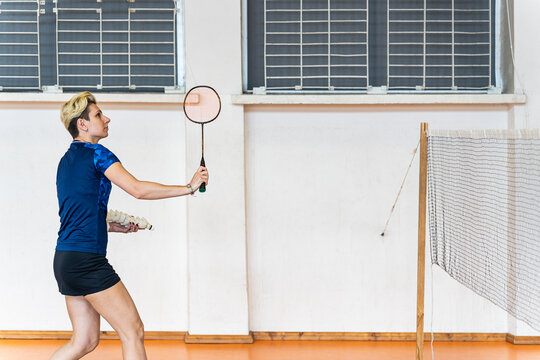Focused woman practicing badminton in a gym