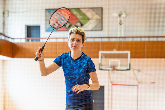 Focused woman athlete swings her badminton racket