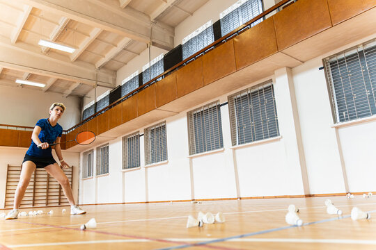 Woman in a low stance playing badminton indoors