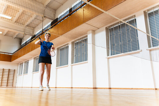 Woman with short hair playing badminton indoors