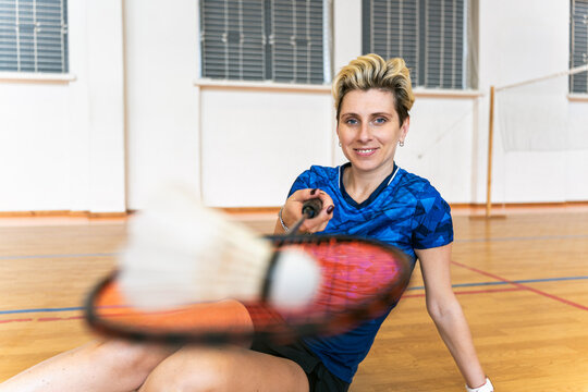 Female badminton player smiles sitting on gym floor