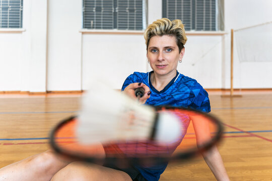 Female badminton player holding shuttlecock to camera