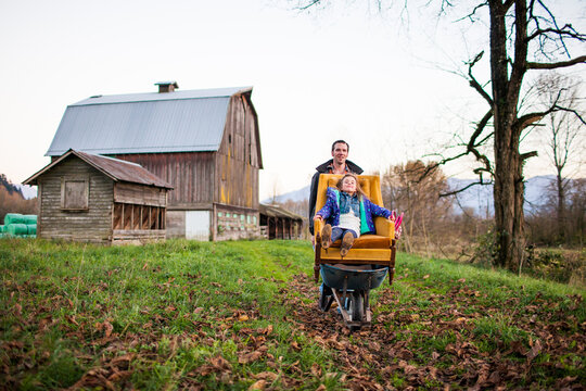 Father pushes daughter in an armchair on a farm