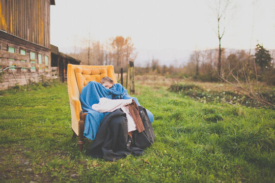 Boy peeks from blankets in a vintage yellow armchair