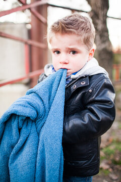 Sad little boy holds his blue security blanket