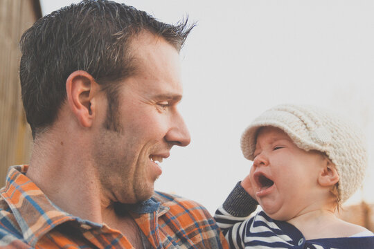 Father smiles while holding his crying baby