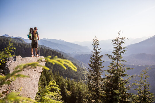 Hiker on a cliff overlooking a mountain range